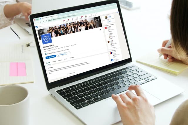 Person managing a Knowcrunch LinkedIn company page on a laptop at a desk.